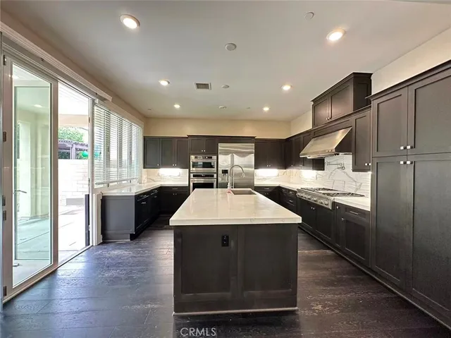 a kitchen with stainless steel appliances granite countertop a sink a stove and a refrigerator