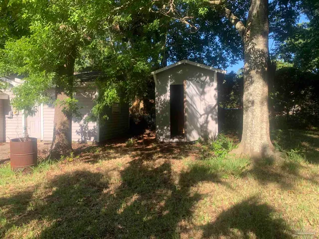 a backyard of a house with table and chairs under an umbrella