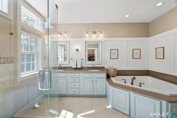 a spacious bathroom with a granite countertop double vanity sink a mirror and a bathtub