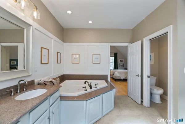 a bathroom with a granite countertop tub and a large mirror