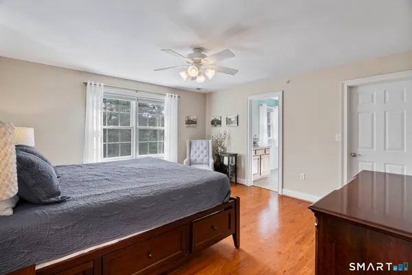 a spacious bedroom with a bed and a dresser with wooden floor