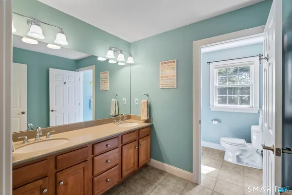 a spacious bathroom with a double vanity sink toilet and a mirror