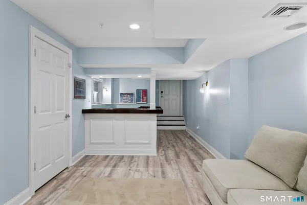 a living room with stainless steel appliances kitchen island granite countertop a refrigerator and a sink