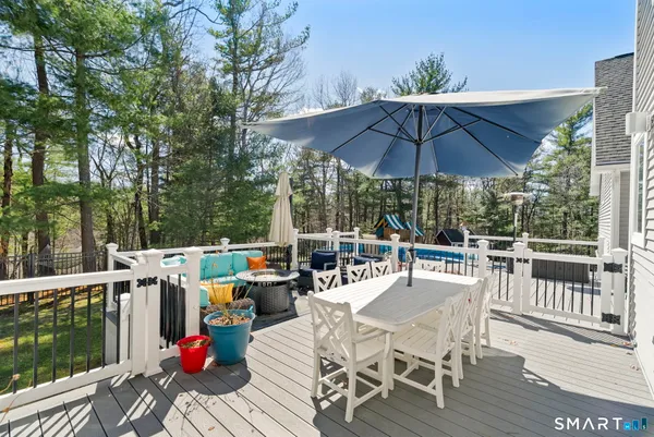 a view of a patio with a dining table and chairs under an umbrella with large trees