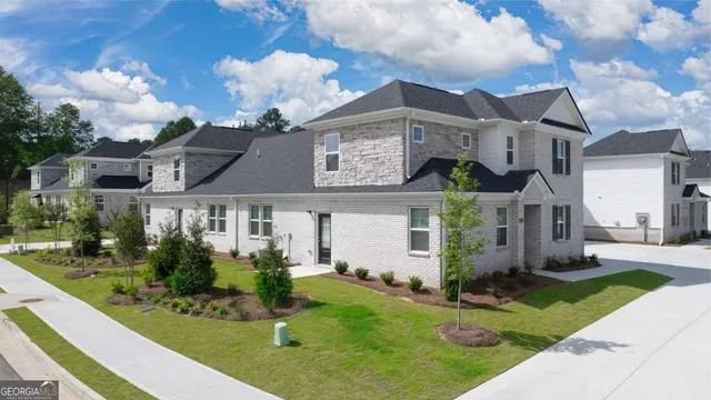 a view of a white house with a big yard and potted plants