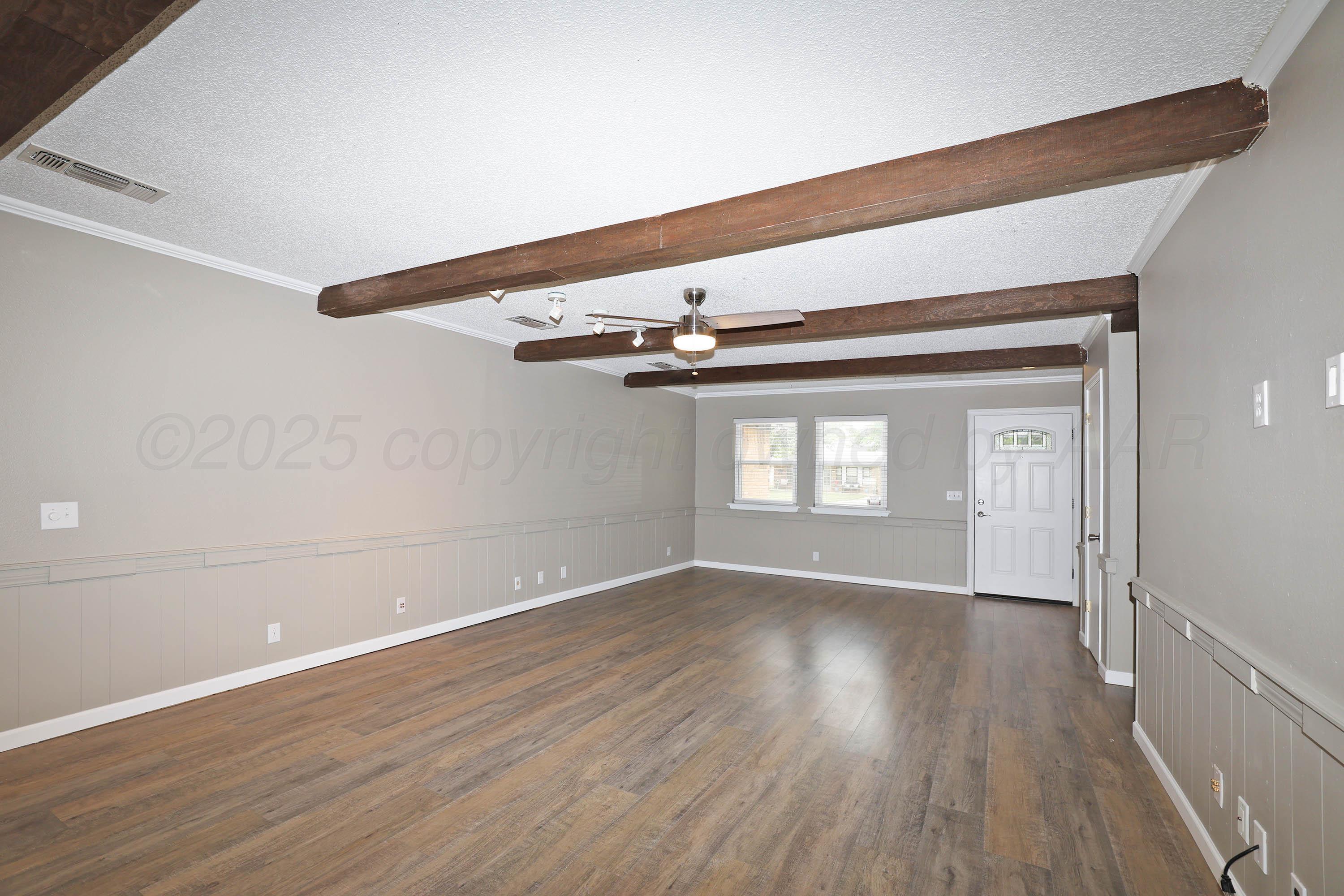 7426 Jameson Drive Amarillo, TX 79121 - Photo 6 of 38 a view of an empty room with wooden floor and a window