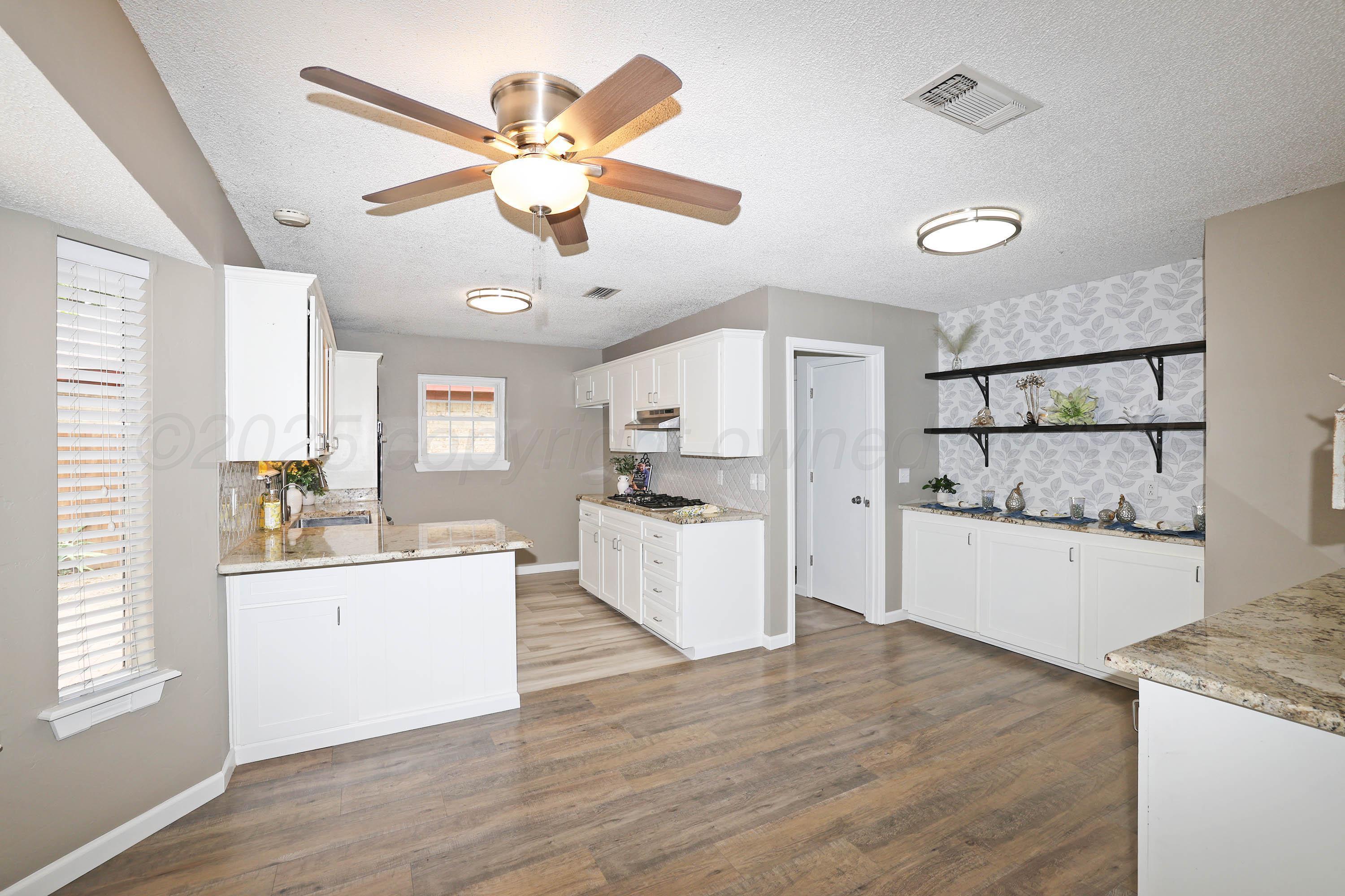 7426 Jameson Drive Amarillo, TX 79121 - Photo 8 of 38 a kitchen with a refrigerator a sink and dishwasher with wooden floor