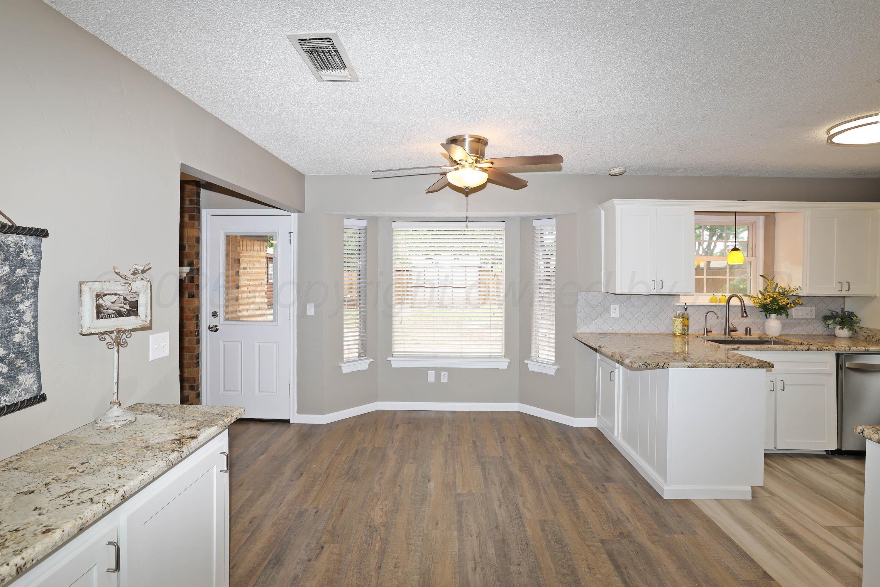7426 Jameson Drive Amarillo, TX 79121 - Photo 9 of 38 a open kitchen with a sink dishwasher a stove and white cabinets with wooden floor