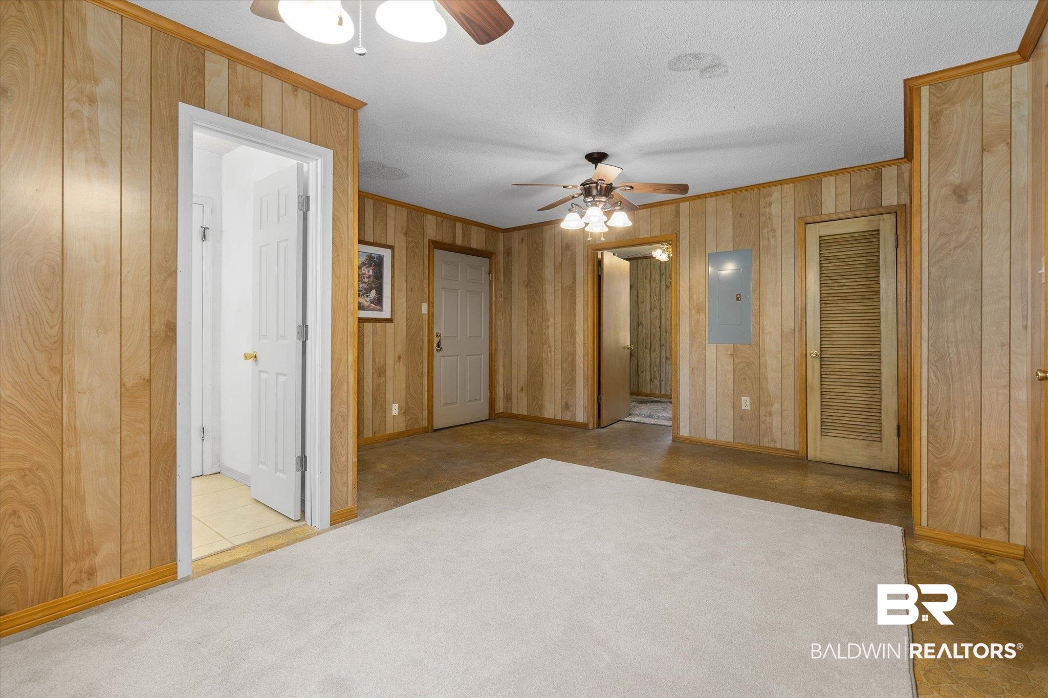 5503 Darring Street Satsuma, AL 36572 - Photo 24 of 31 Unfurnished bedroom with ornamental molding, electric panel, ensuite bathroom, wooden walls, and a textured ceiling