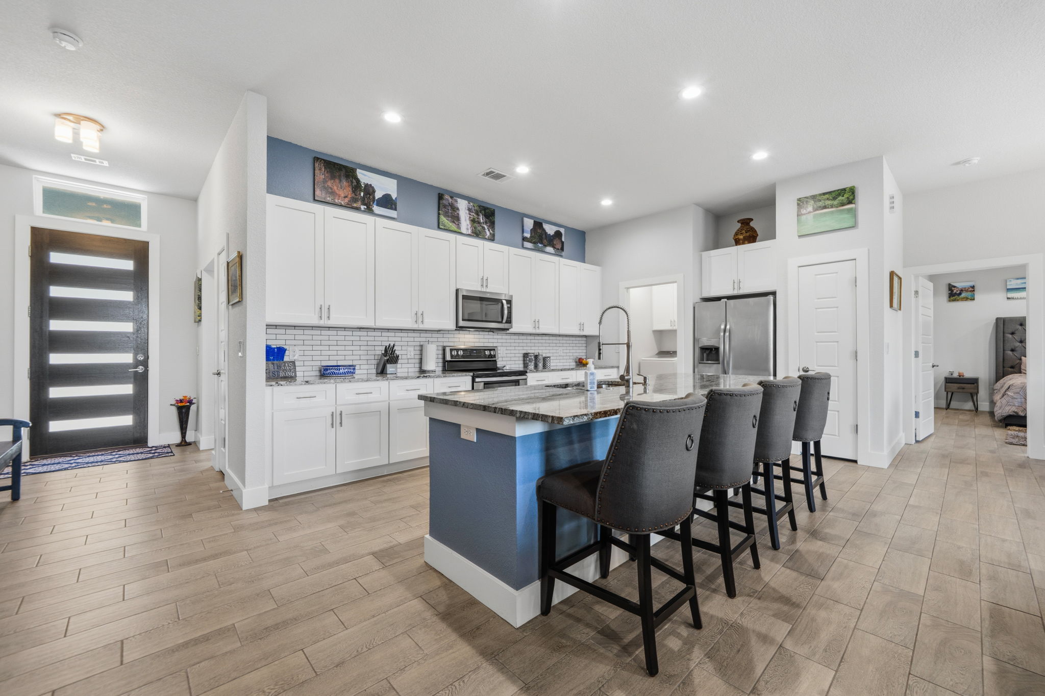 18605 Masters Cove Point Venture, TX 78645 - Photo 9 of 40 Modern kitchen featuring white shaker cabinetry, stainless steel appliances, a subway tile backsplash, and a central island with bar seating and a stone-finish countertop
