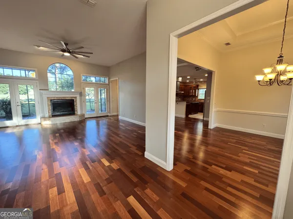 a view of an empty room with wooden floor fireplace and a window