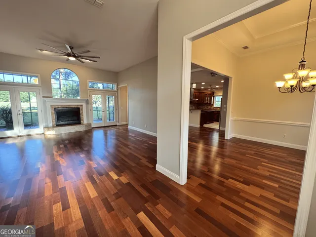 a view of an empty room with wooden floor fireplace and a window
