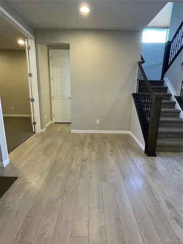 a view of an empty room with wooden floor and stairs