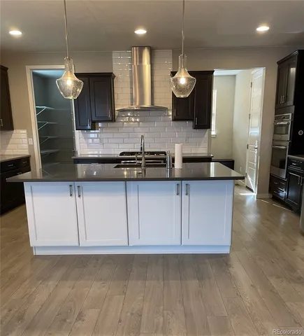 a large kitchen with stainless steel appliances kitchen island granite countertop a sink a stove a microwave a counter and a view of living room