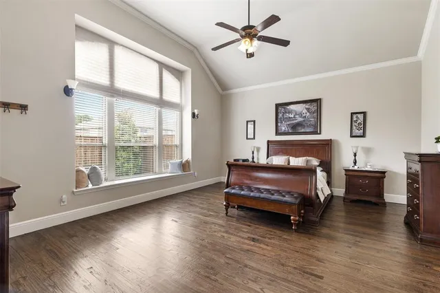 a spacious bedroom with a bed a dresser and wooden floor