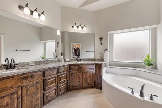 a bathroom with a granite countertop bathtub a double vanity sink and a large mirror