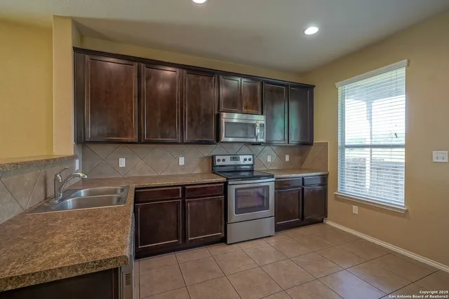a kitchen with stainless steel appliances granite countertop a stove sink and cabinets
