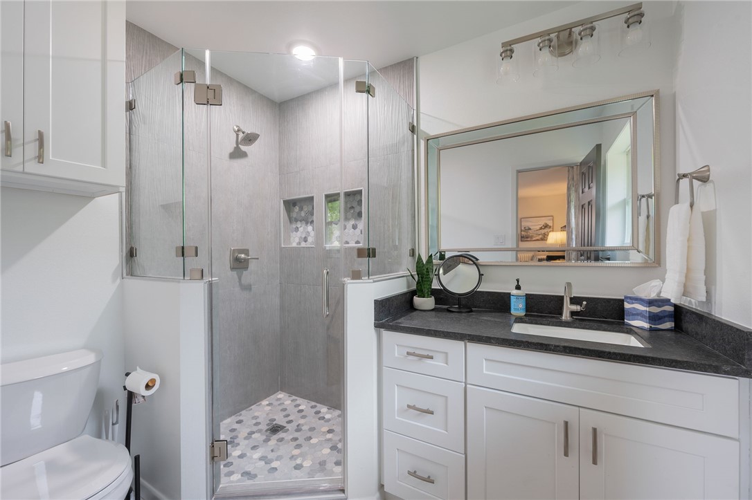 1509 Barak Lane Bryan, TX 77802 - Photo 17 of 24 a bathroom with a granite countertop sink a toilet a large mirror a shower and vanity