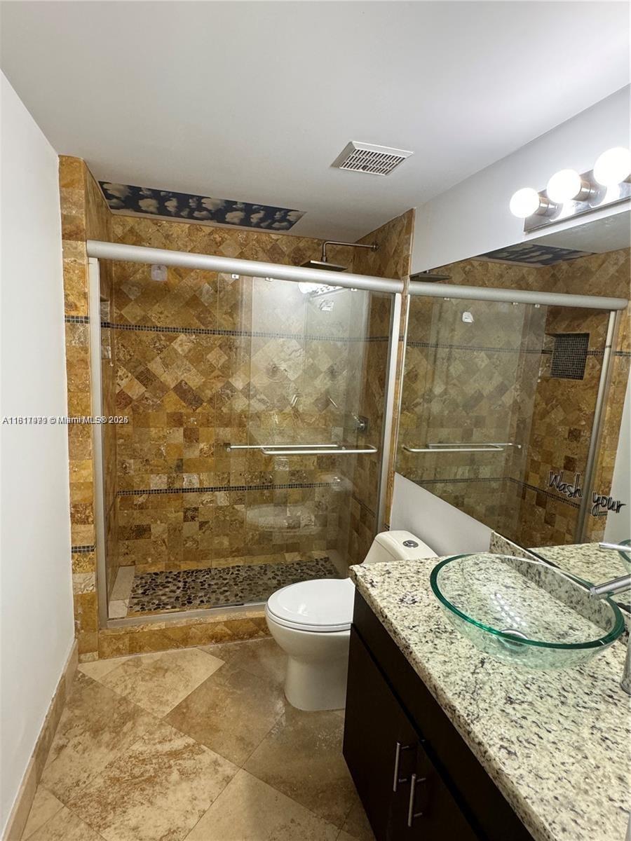 5091 Northwest 7th Street, Unit 615 Miami, FL 33126 - Photo 22 of 40 a bathroom with a granite countertop sink a toilet a mirror and shower