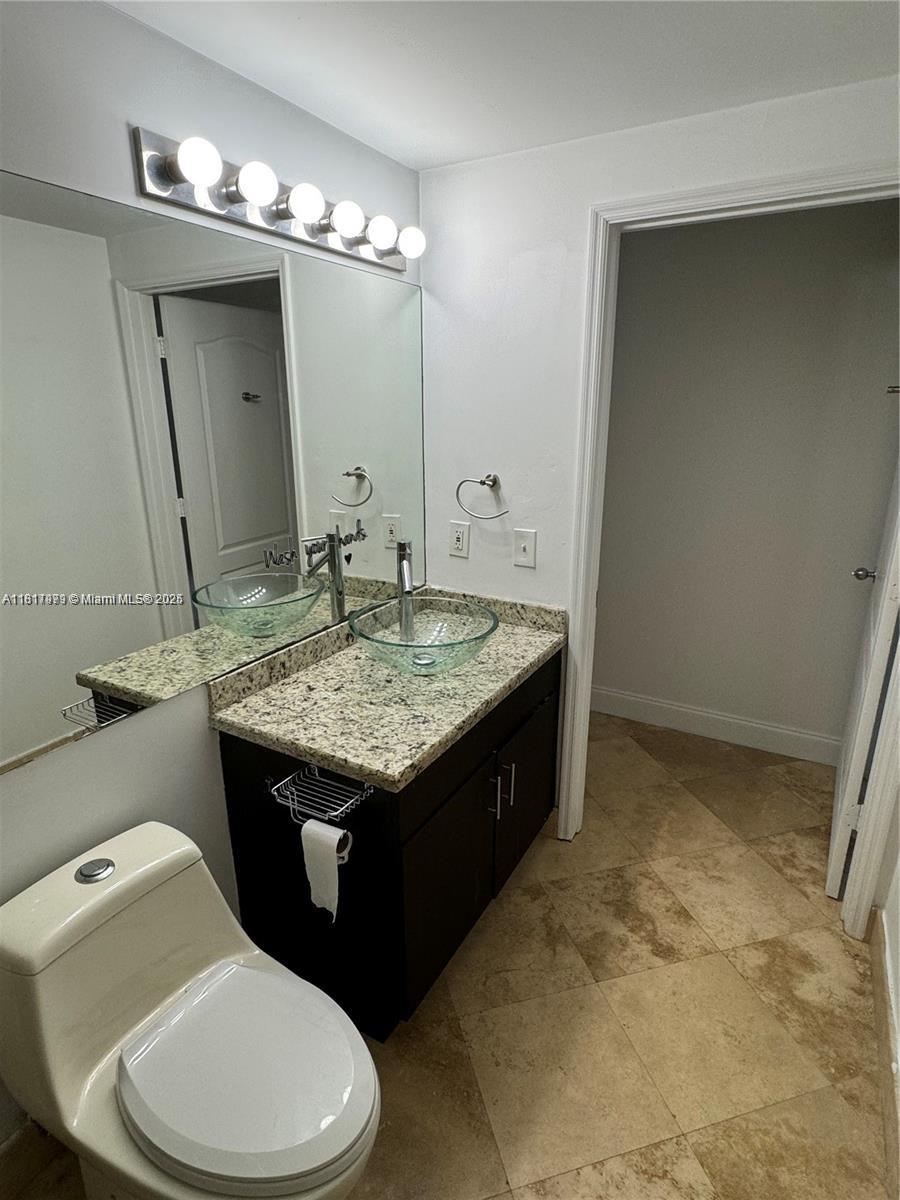 5091 Northwest 7th Street, Unit 615 Miami, FL 33126 - Photo 24 of 40 a bathroom with a granite countertop sink and a mirror