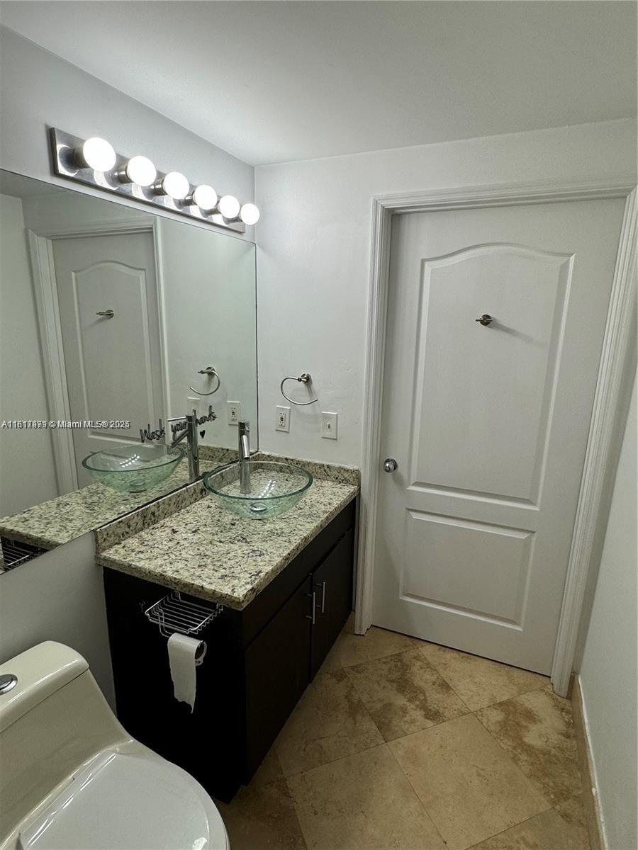5091 Northwest 7th Street, Unit 615 Miami, FL 33126 - Photo 25 of 40 a bathroom with a granite countertop sink and a mirror