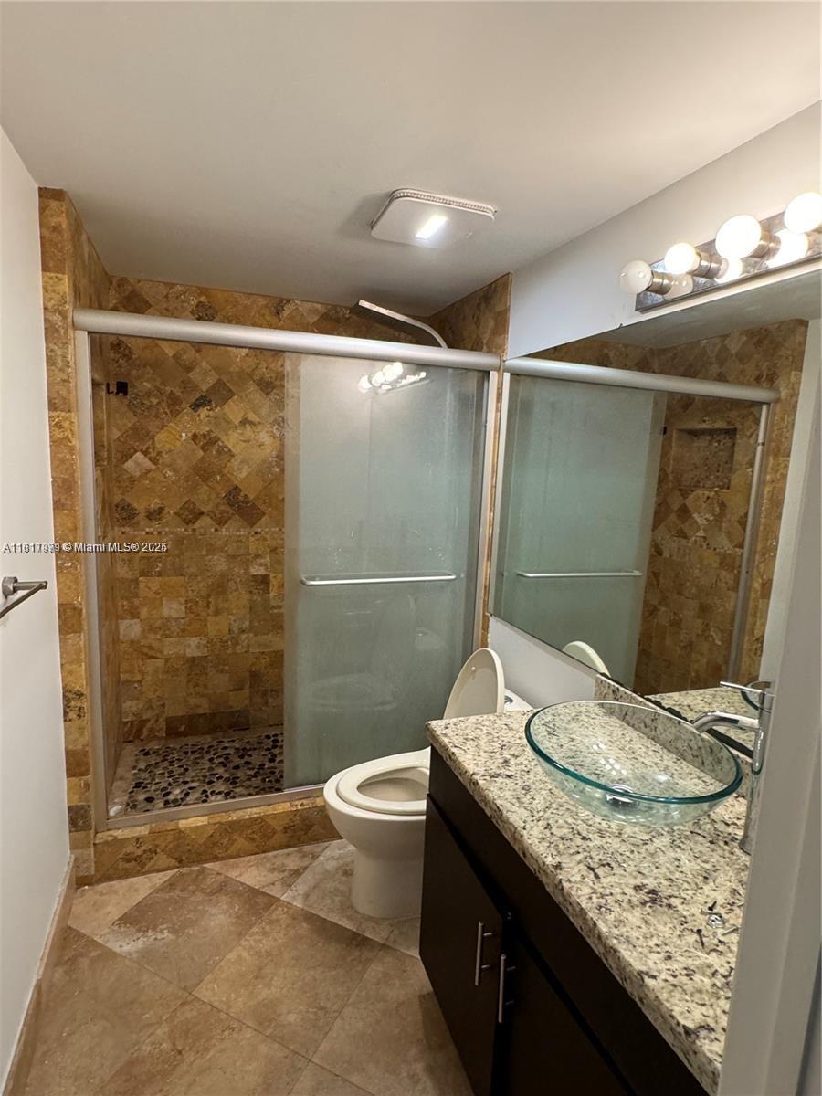 5091 Northwest 7th Street, Unit 615 Miami, FL 33126 - Photo 26 of 40 a bathroom with a granite countertop sink toilet and shower