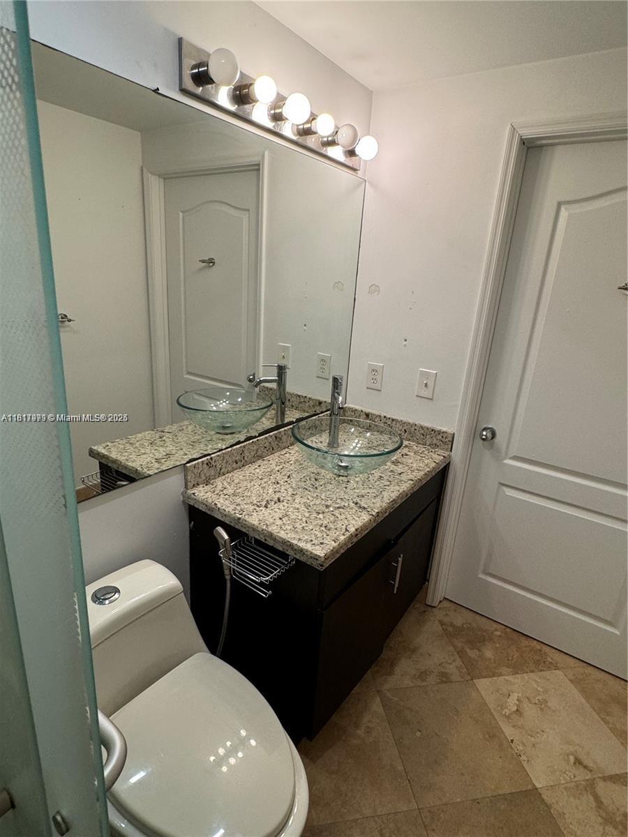 5091 Northwest 7th Street, Unit 615 Miami, FL 33126 - Photo 28 of 40 a bathroom with a granite countertop sink and a mirror