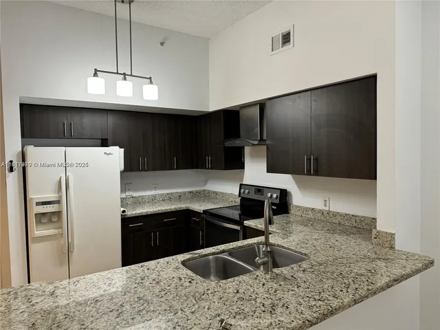 a kitchen with stainless steel appliances granite countertop a sink a refrigerator and a stove