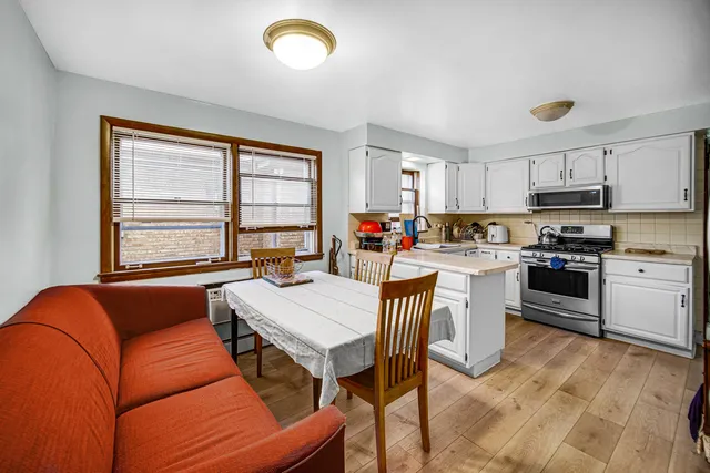 a view of kitchen with kitchen island a stove a sink a dining table and chairs