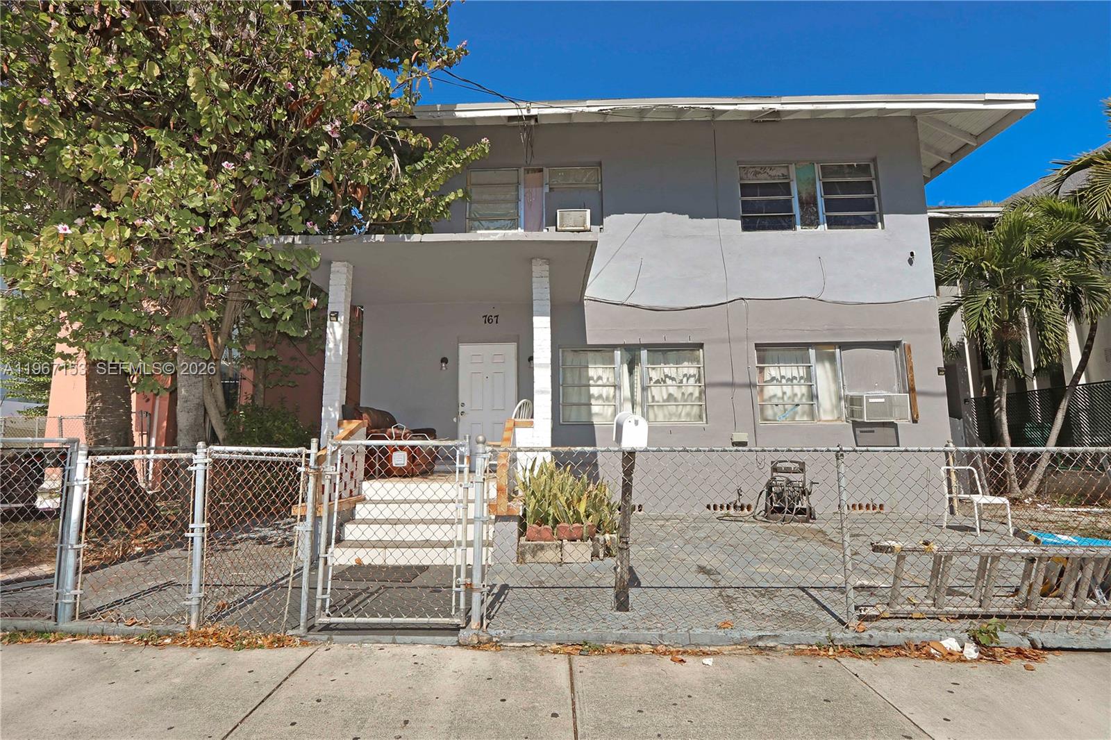 a view of a white house with large windows and plants
