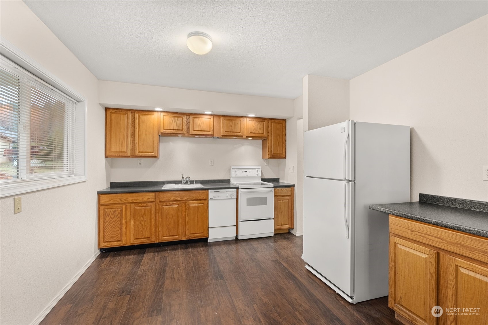 2131 Stuart Street Raymond, WA 98577 - Photo 4 of 25 a kitchen with granite countertop wooden floors and white stainless steel appliances