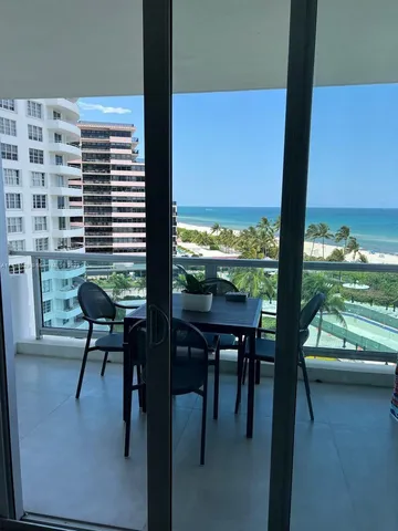 a view of a patio with lawn chairs floor to ceiling window and an outdoor kitchen