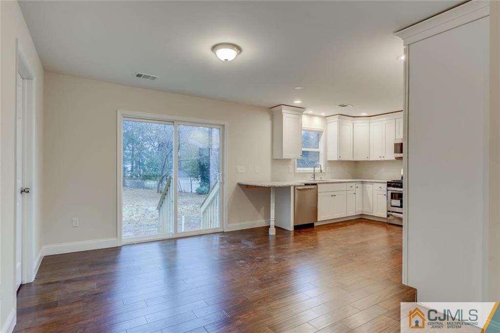 41 Emerson Road Somerset, NJ 08873 - Photo 8 of 25 a large white kitchen with kitchen island a sink dishwasher a stove and a refrigerator with wooden floor