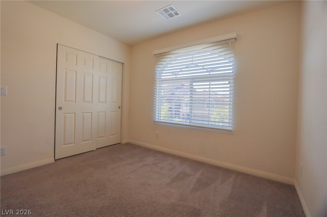 6418 Jackson Spring Road Las Vegas, NV 89118 - Photo 12 of 20 A well-lit bedroom featuring soft carpeting and a window with blinds, offering serene views.