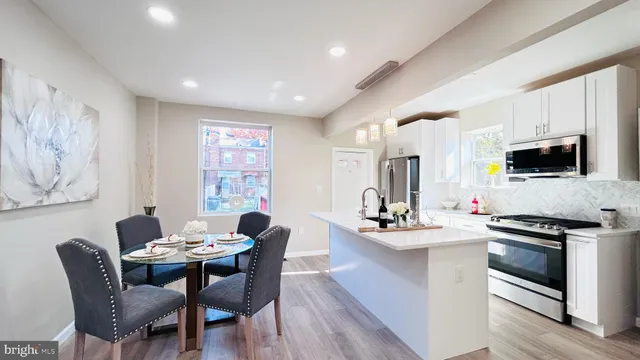 a dining room with stainless steel appliances kitchen island granite countertop a dining table chairs and a refrigerator