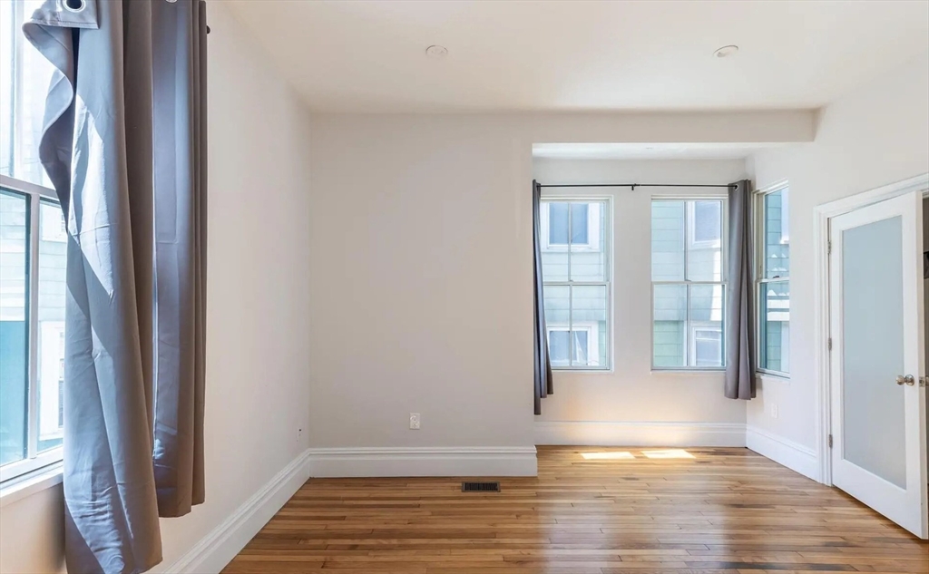 89 Cedar Street, Unit 2 Boston, MA 02119 - Photo 20 of 27 a view of an empty room with wooden floor and a window
