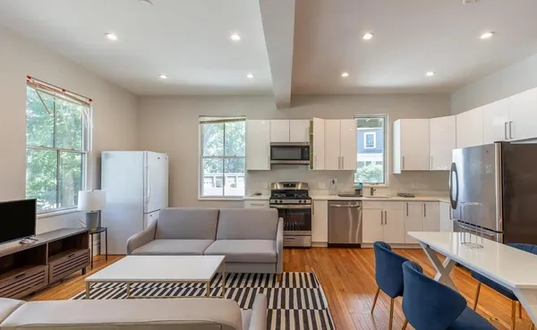 a living room with stainless steel appliances furniture or couch and a flat screen tv