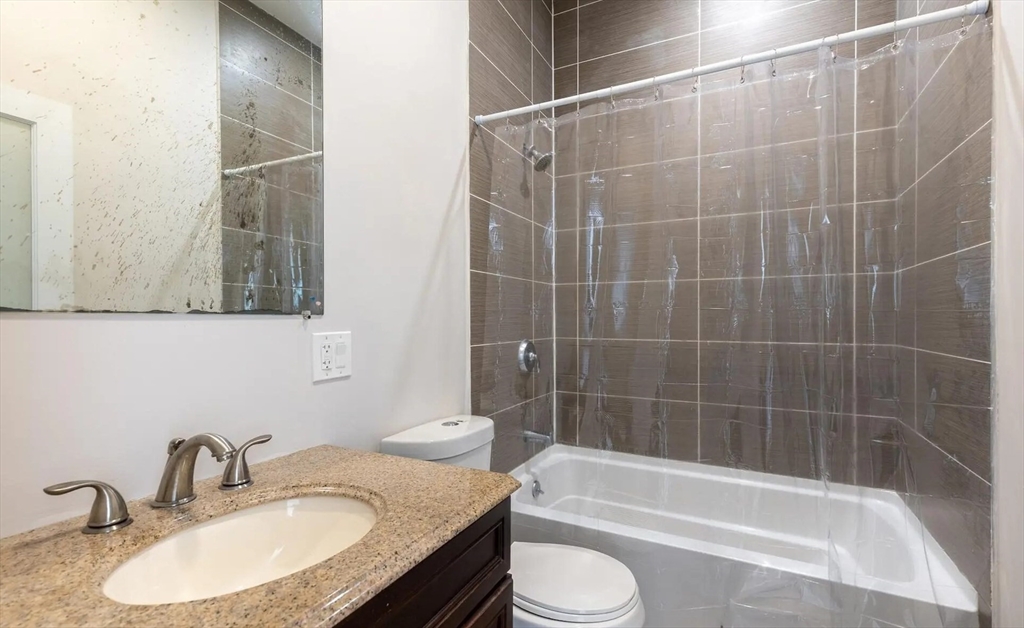 89 Cedar Street, Unit 2 Boston, MA 02119 - Photo 23 of 27 a bathroom with a granite countertop sink toilet and shower