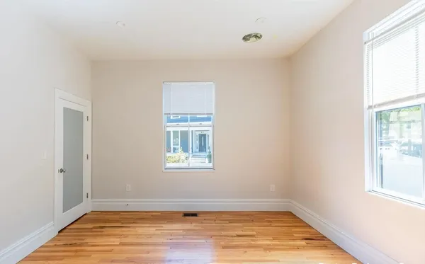 an empty room with wooden floor and windows