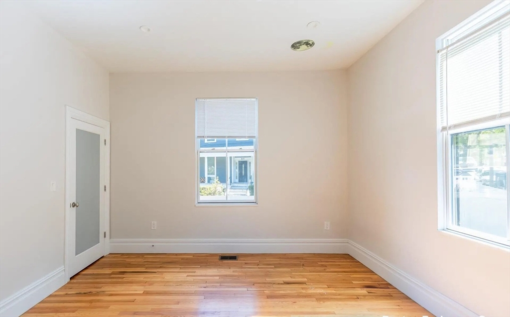 89 Cedar Street, Unit 2 Boston, MA 02119 - Photo 10 of 27 an empty room with wooden floor and windows