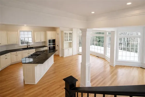 a large white kitchen with wooden floor and a large window