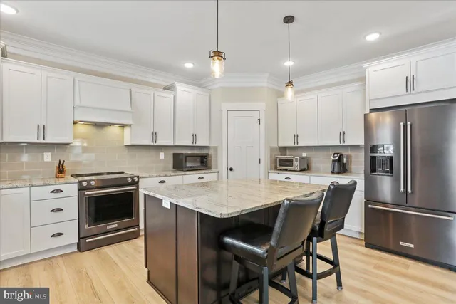 a kitchen with a refrigerator a stove a sink and white cabinets with wooden floor