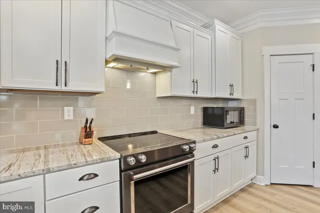 a kitchen with granite countertop white cabinets and white appliances