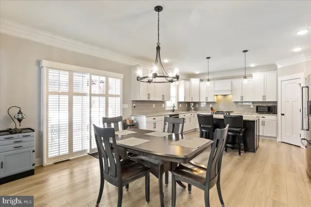 a dining room filled chandelier and wooden floor
