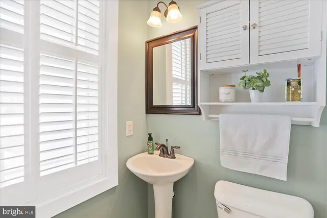 a bathroom with a sink a mirror a window and a toilet