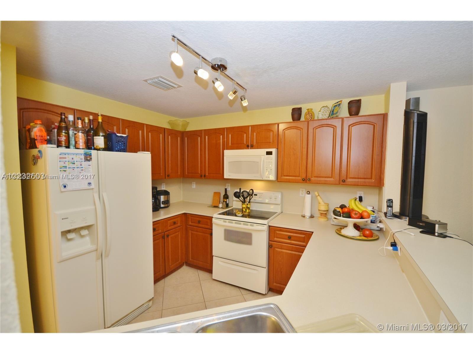 3153 Southwest 129th Terrace, Unit 161 Miramar, FL 33027 - Photo 5 of 17 a kitchen with a refrigerator a stove top oven a sink and cabinets