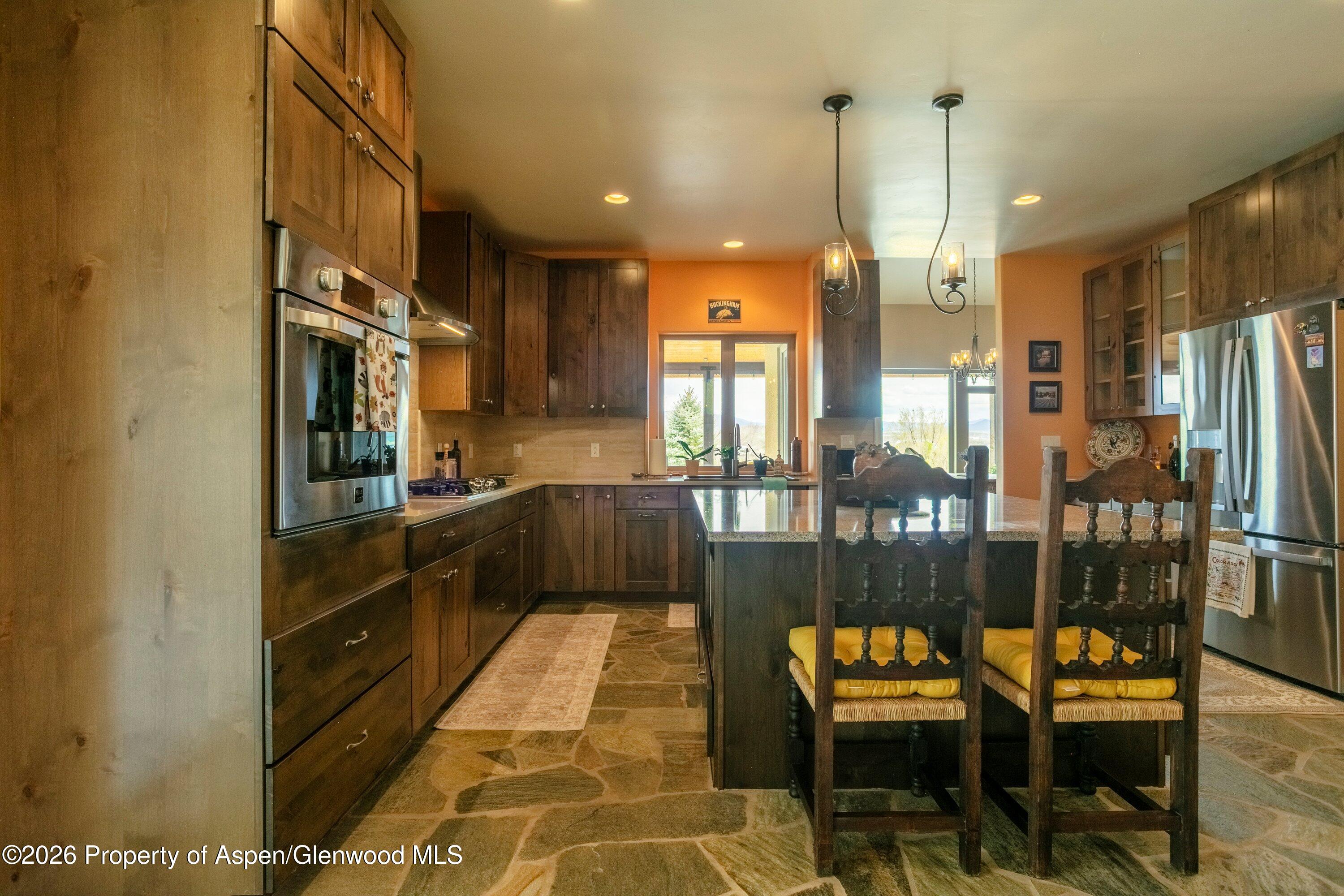 265 South Meadow Drive Rifle, CO 81650 - Photo 45 of 76 a kitchen with stainless steel appliances kitchen island granite countertop dining table chairs and granite counter tops