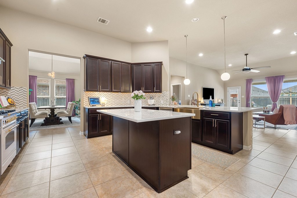 13808 Field Stream Lane Manor, TX 78653 - Photo 11 of 39 Kitchen featuring a center island, dark wood finish cabinets, pendant lighting, a peninsula, and backsplash