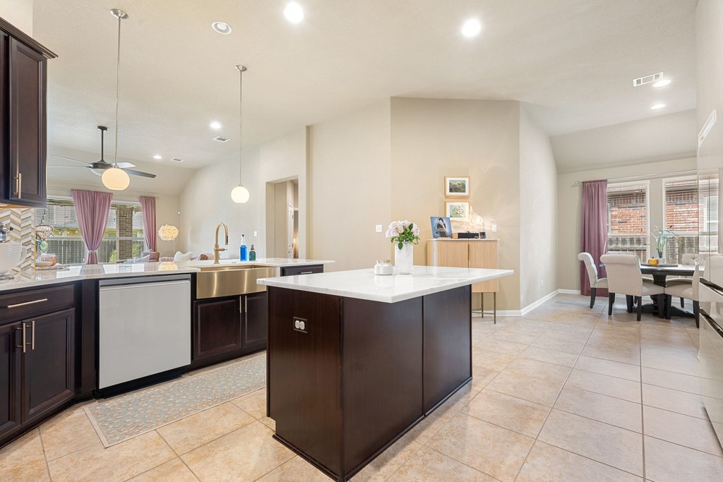 13808 Field Stream Lane Manor, TX 78653 - Photo 13 of 39 Kitchen featuring dark wood finish cabinets, dishwasher, light stone countertops, vaulted ceiling, and light tile patterned floors