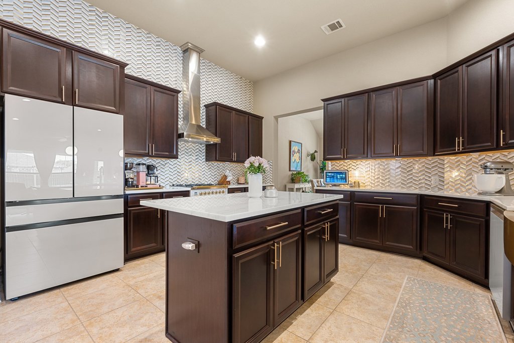 13808 Field Stream Lane Manor, TX 78653 - Photo 2 of 39 Kitchen with freestanding refrigerator, dark wood finish cabinets, a kitchen island, light tile patterned floors, and light stone counters